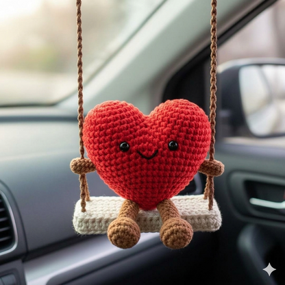 Crocheted heart-shaped character on a swing inside a car